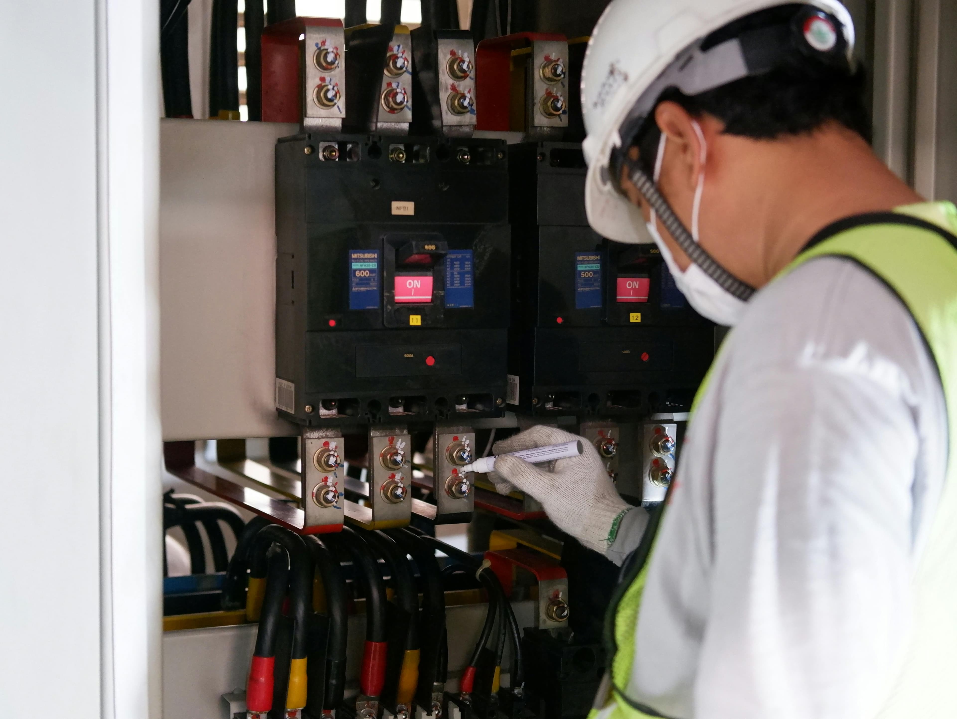 Technician inspecting an industrial electrical panel with care