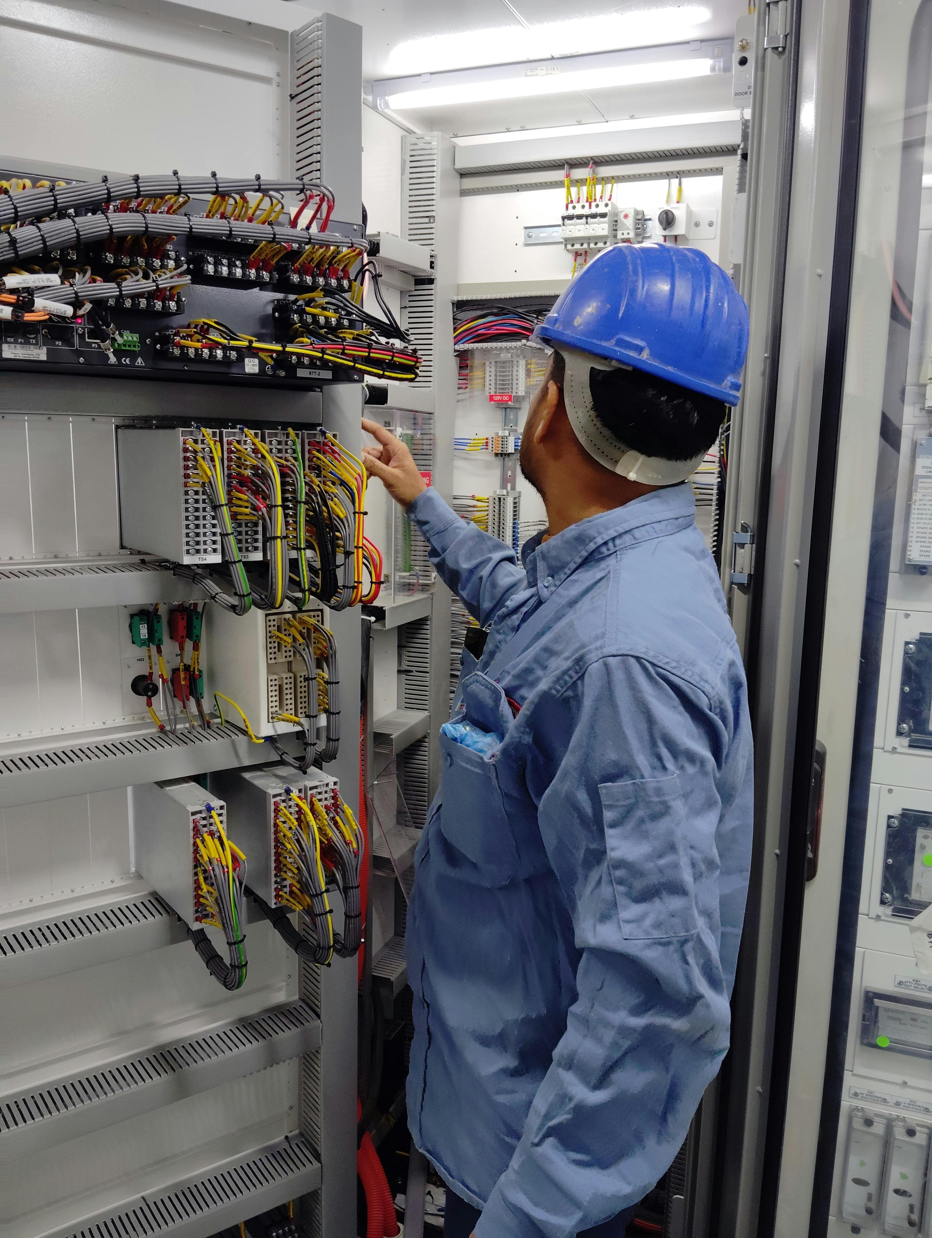 Technician working on organized wiring inside a power controls panel